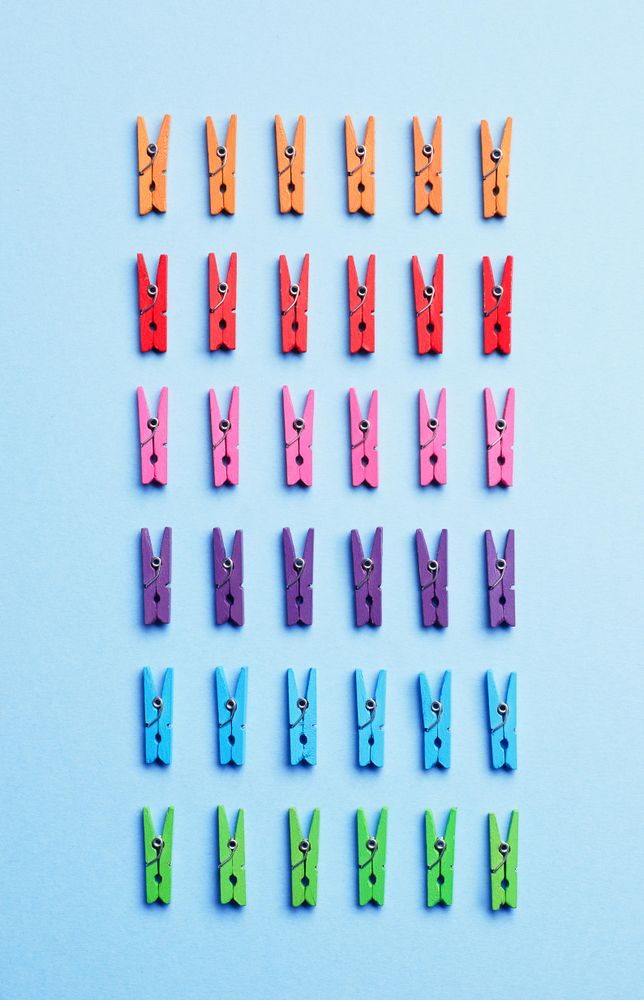 Rainbow colored clothes pins on light blue background