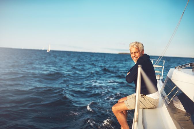 Man sitting on edge of sailing yacht on clear day
