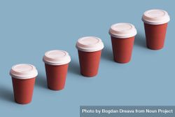 Single row of disposable coffee cups on blue background 0LYMr5