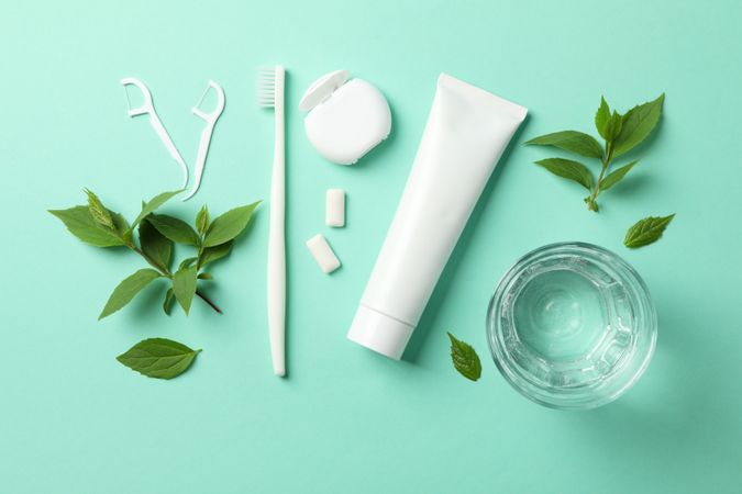 Tools for dental care on mint background, top view