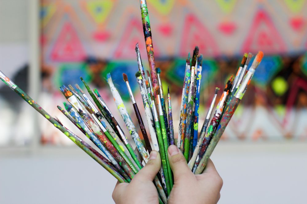 Hands holding painting brushes