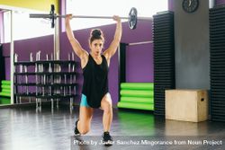 Fit woman lifting barbell over her head in gym 49QOL4