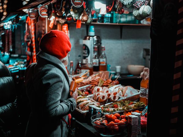 Back view of woman standing in front of food display at the street market at night in Ukraine