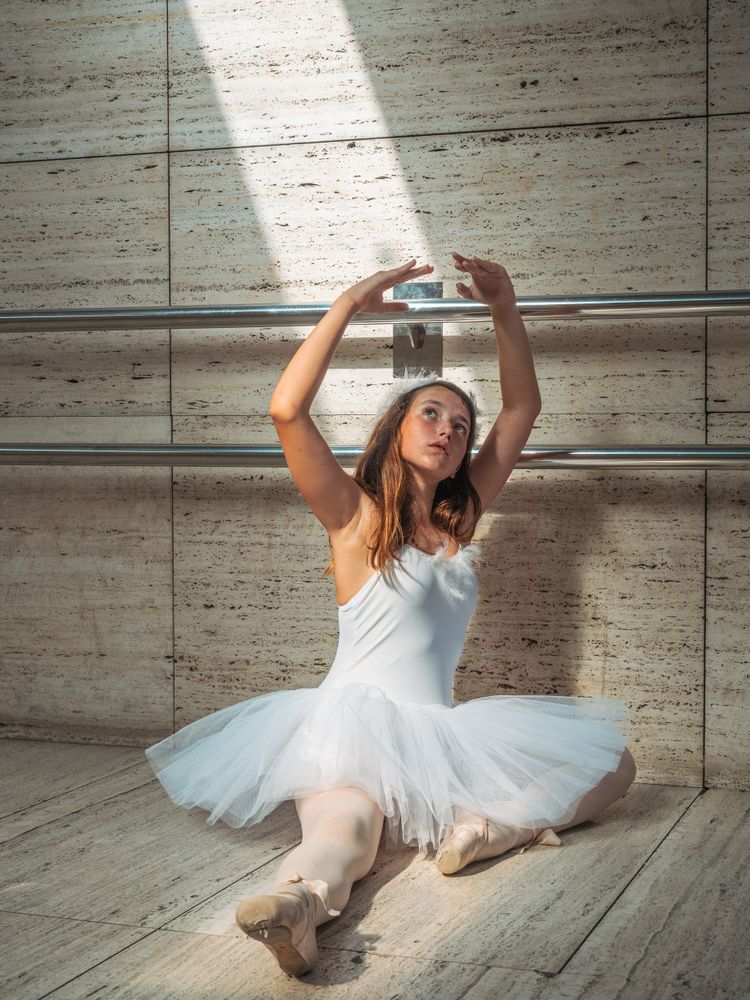 Ballerina sitting on floor stretching graceful leg