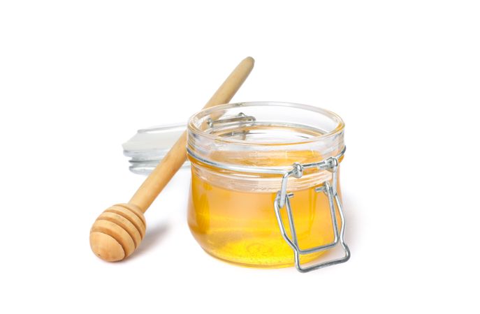 Dipper and glass jar with honey isolated on blank background
