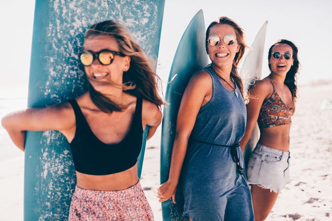 Group of smiling young women with surf boards at the beach