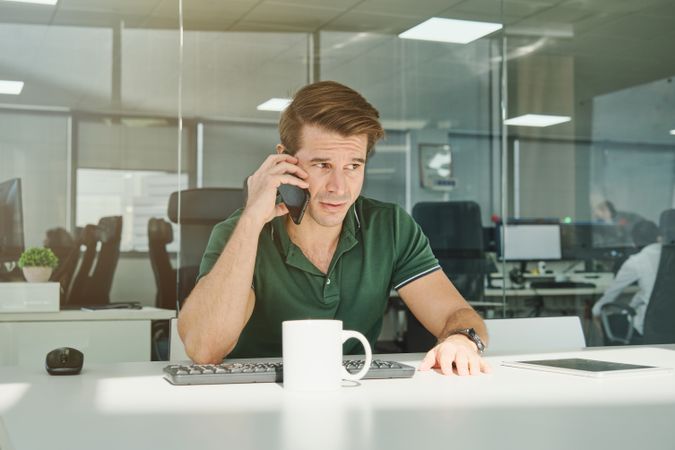 Guy speaking on cellphone in modern office
