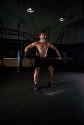 Muscular professional male athlete lifting barbell with weights