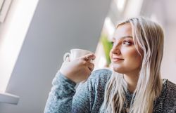 Positive woman holding cup in office