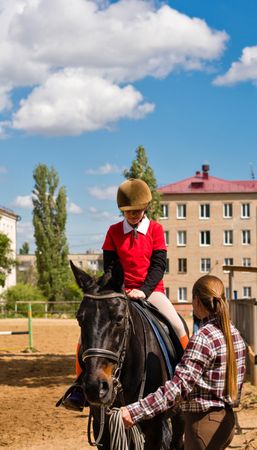 Young equestrian receives instruction during horseback riding session.
