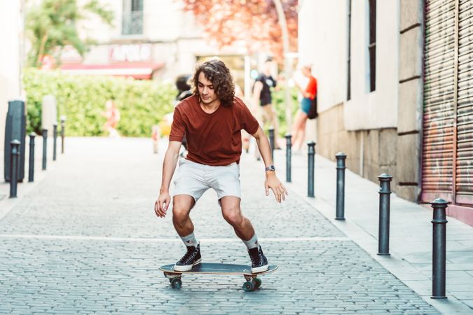 Confident man riding longboard across city street