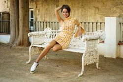 Smiling woman sitting on bench holding her hair and looking at camera