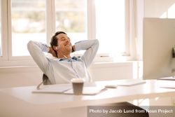 Smiling businessman resting in office chair at home office 0gj73b