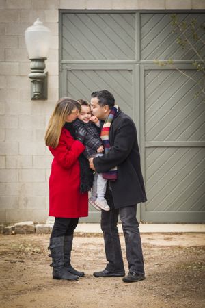 Warmly Dressed Family Loving Son in Front of Rustic Building