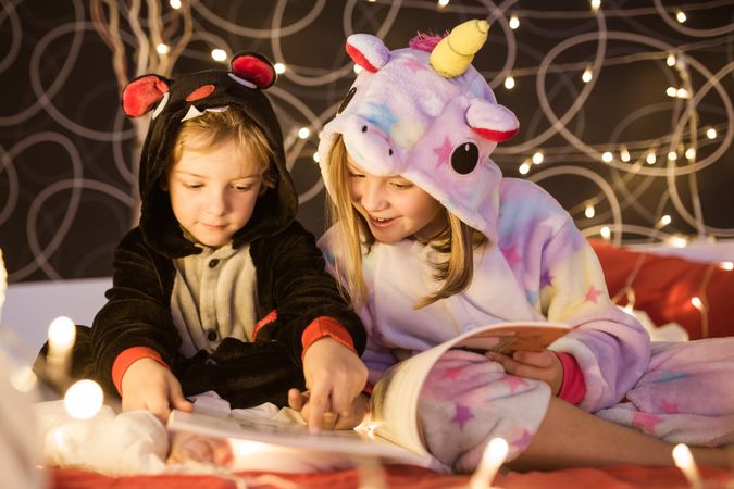 Kids reading Christmas fairy tales in bed
