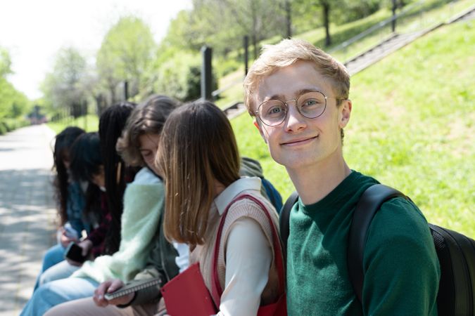 Portrait of man sitting on campus with his multi-ethnic cohort of students