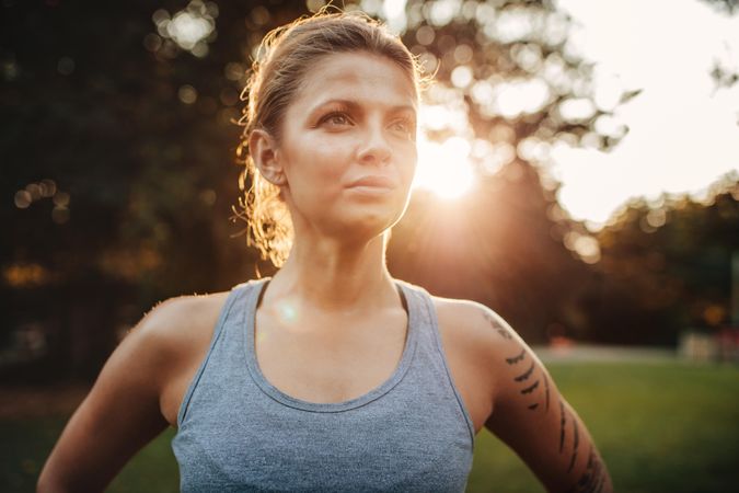 Close up portrait of healthy young woman in sportswear standing outdoors and looking away