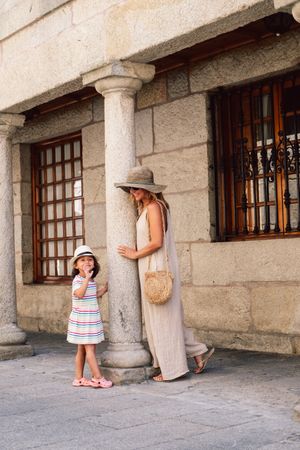 Mother and daughter walking in street along ancient building