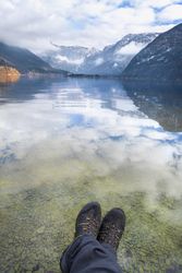 POV of man’s legs relaxing over Alpoine lake