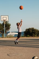 Boy playing basketball on sports ground