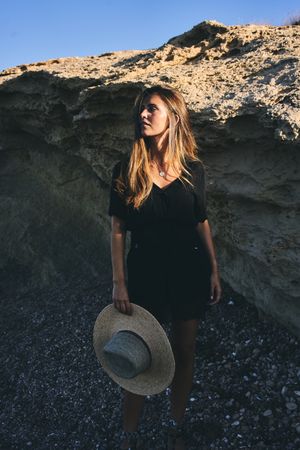 Cheerful woman holding hat in air