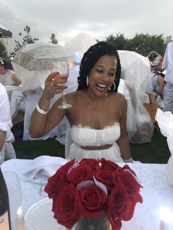 Bride smiling and holding a glass of wine surrounded by guests