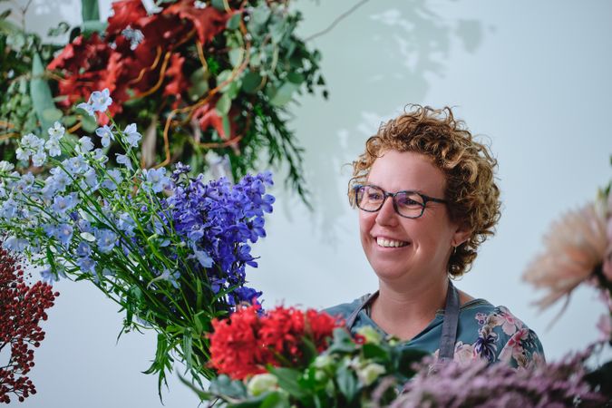 Happy woman with blooming flowers in floral shop