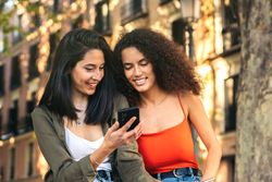 two young women sitting watching something on the mobile