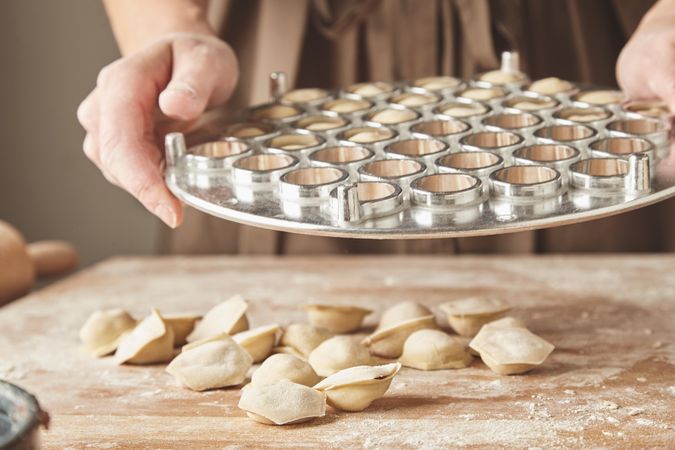 Hands holding tray of ravioli molds