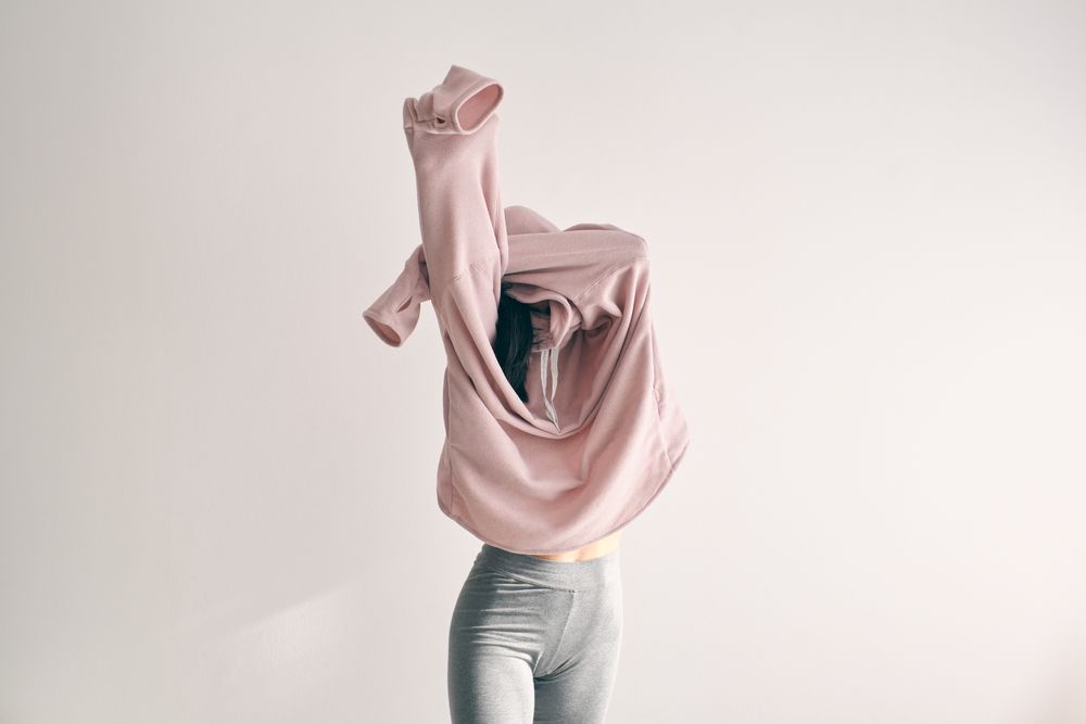 Woman covering face with sweater in studio