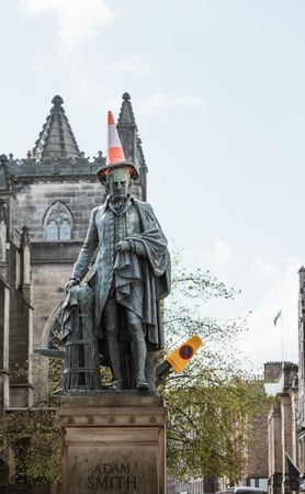 Aged monument with road cone on head