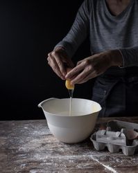 Person cracking egg in bowl on table
