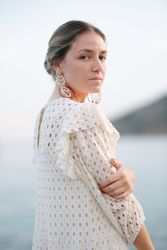 Feminine woman in stylish dress standing near sea during vacation