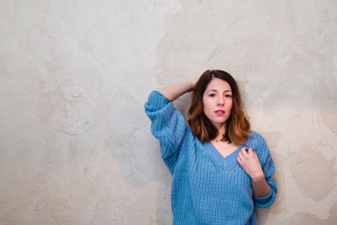 Charming woman in sweater near wall