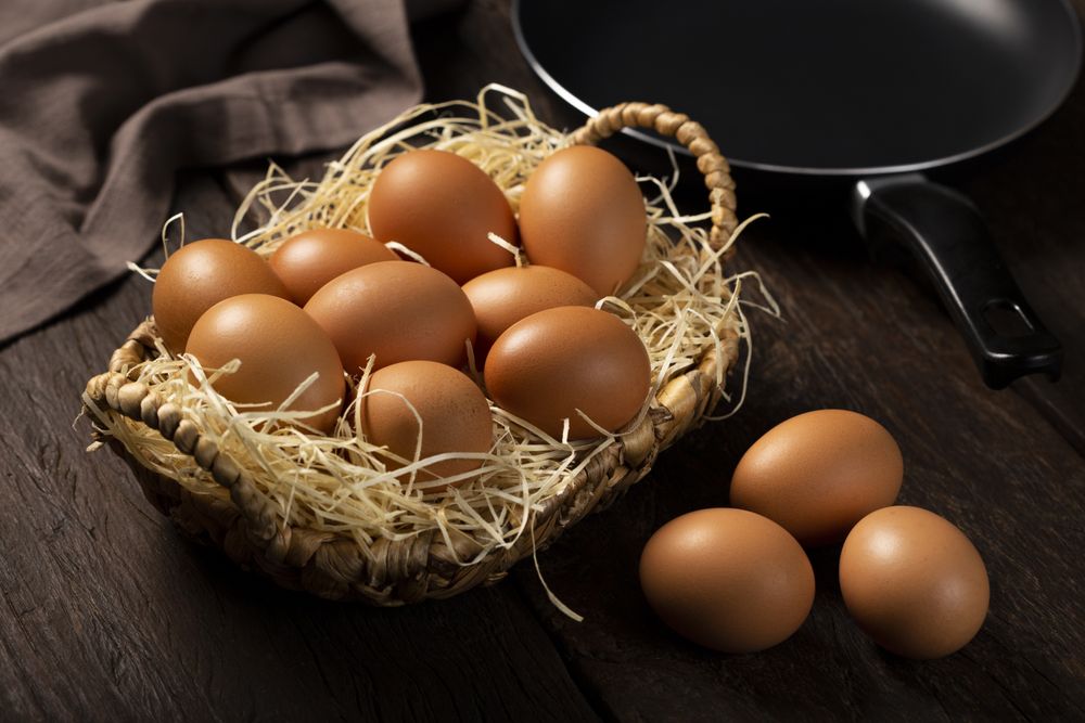 Basket with brown chicken eggs goes up the table.