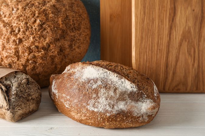 Bakery products and cutting boards on wooden table against light background, space for text and closeup