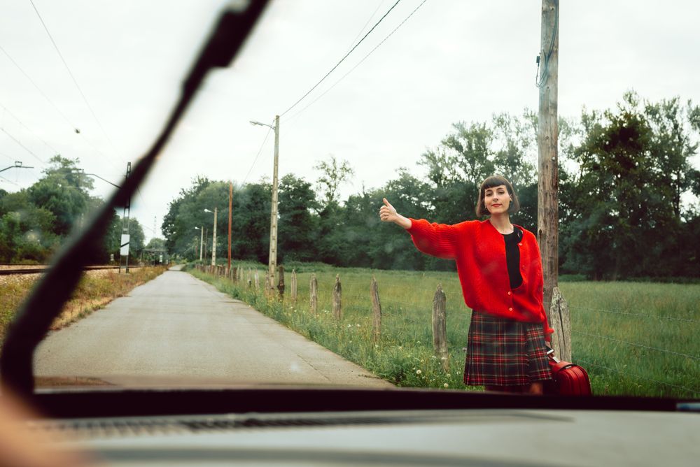 Woman in red sweater catching car on road