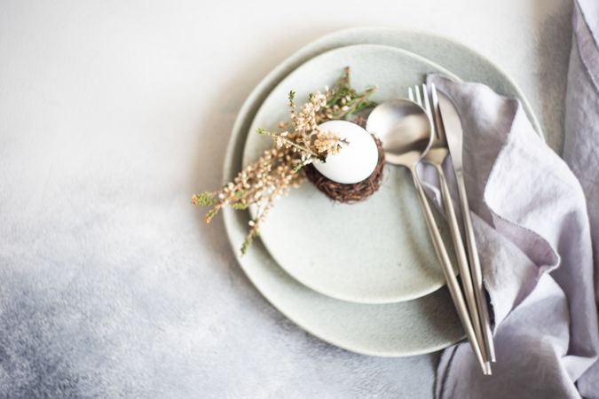 Top view of Easter table setting with decorative nest & egg, with heather on plates