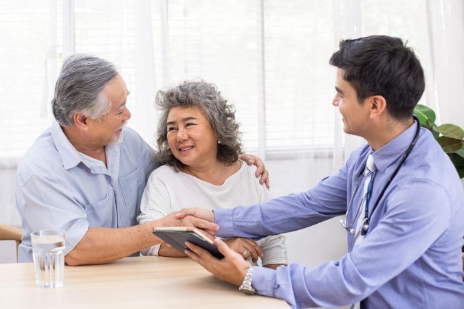 Doctor using digital tablet discussing prognosis with Asian patients