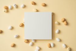 Easter eggs on pastel yellow background with paper card note