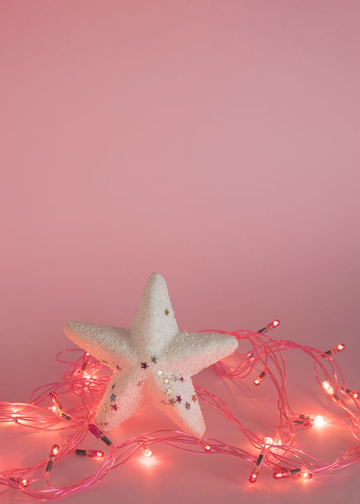 Star surrounded by fairy lights on pink background