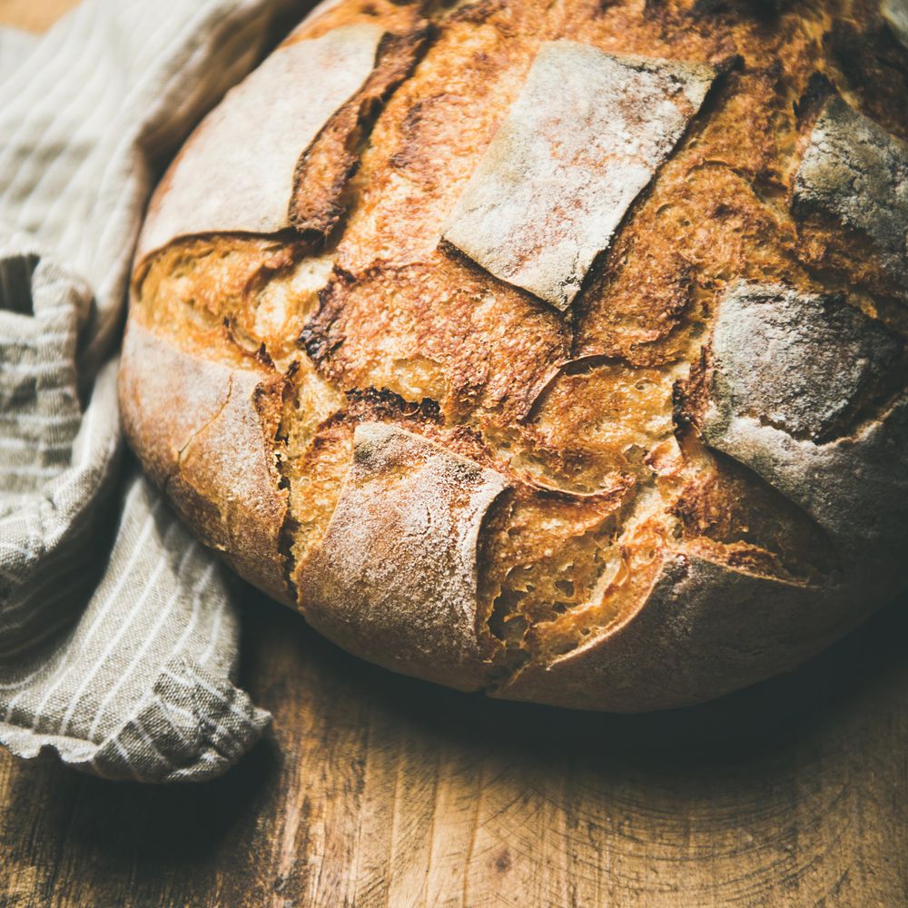 Close up of scoring on homemade loaf of bread on bread board, square crop