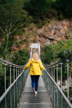 Cheerful female tourist standing on hanging bridge in summer