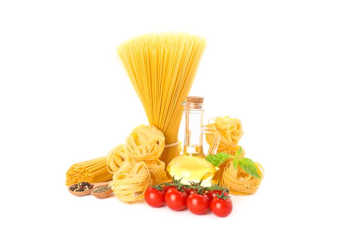 Pasta, olive oil, tomatoes and spice isolated on light background. Uncooked whole wheat pasta