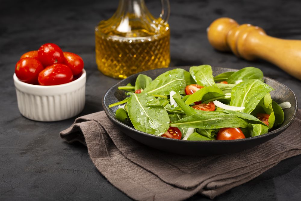 Arugula salad with tomatoes on dark background.
