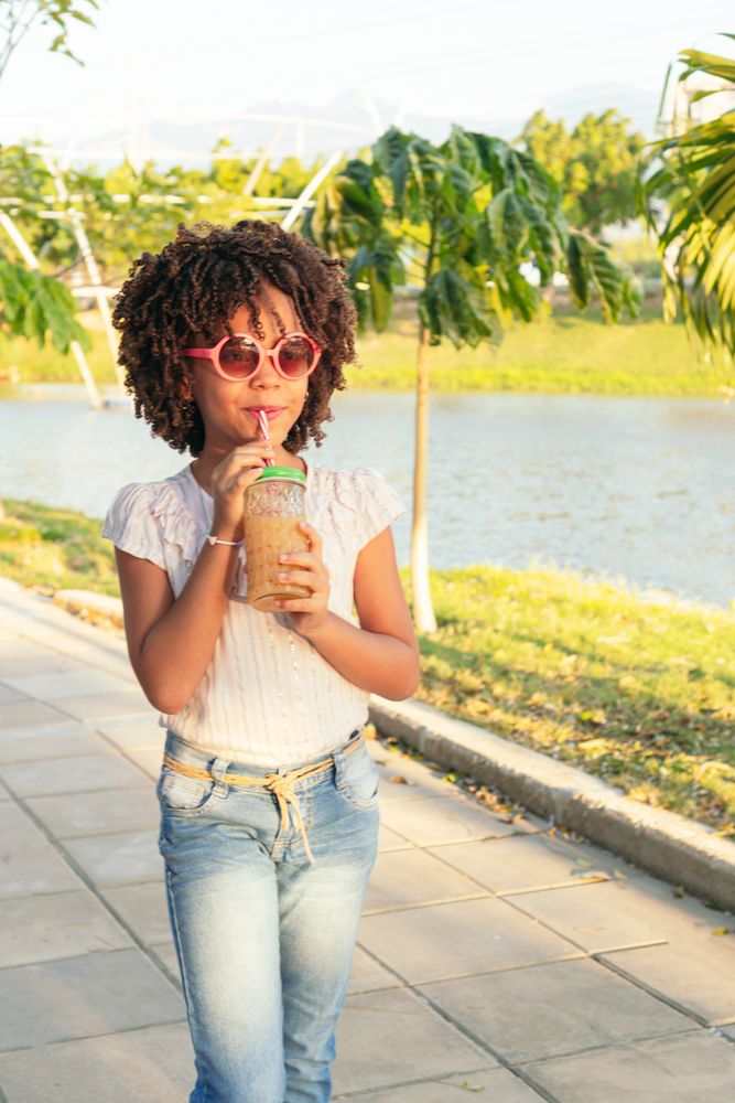Girl walking in the park while drinking juice