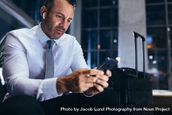 Businessman sitting at airport lounge and texting in his mobile phone 4987Q5