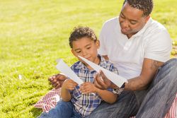 Father and Son Playing with Paper Airplanes in park