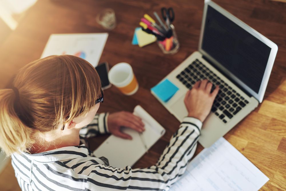 Looking down at woman in striped shirt working on laptop