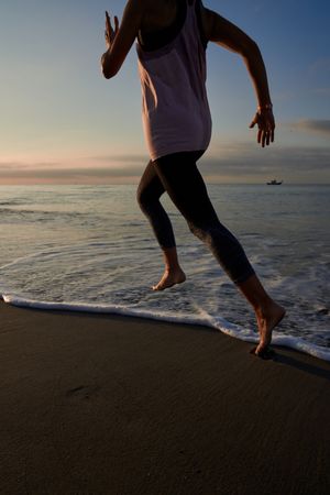 Anonymous woman running on seacoast at sundown time